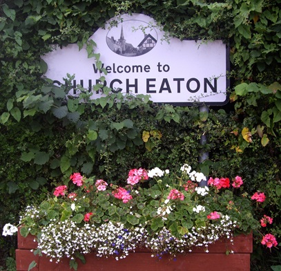 Image of flowers in a planter under a Welcome to Church Eaton sign